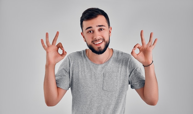 I am ok. Happy businessman, sign ok, smiling, isolated on gray studio background. Beautiful male half-length portrait. Emotional man. Human emotions, facial expression concept. Front