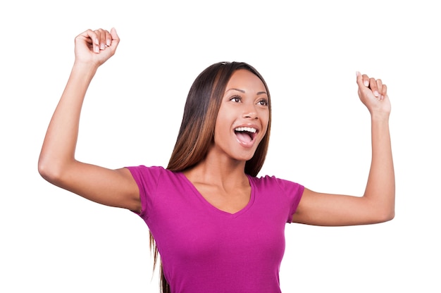 I am so happy! Beautiful young African woman keeping her arms raised and expressing positivity while standing isolated on white