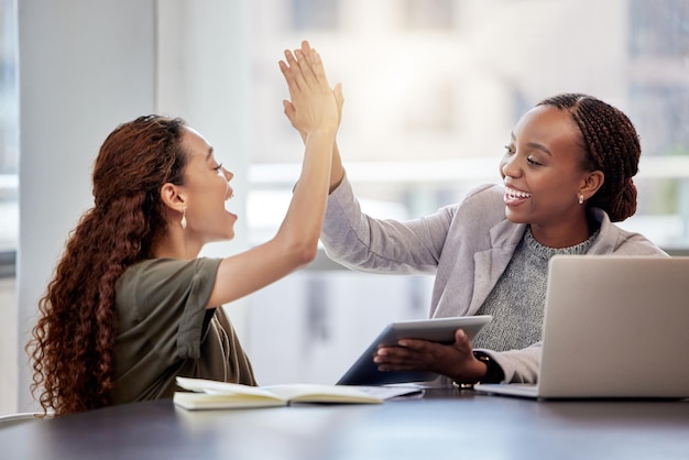 I couldnt have done it without you Shot of two young female colleagues giving each other a high five in an office at work