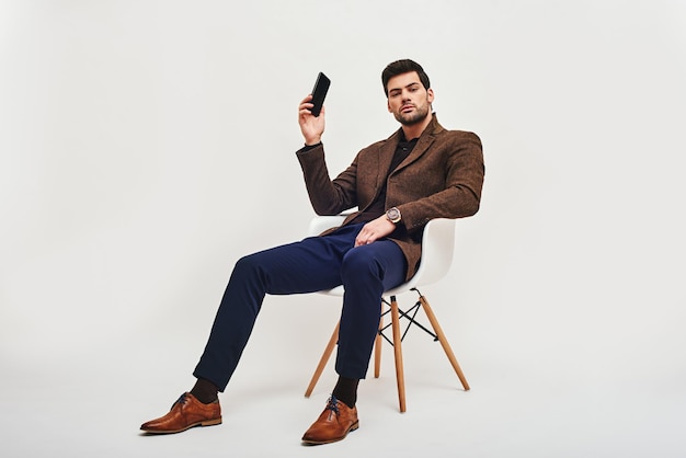 I have an idea stylish darkhaired man sitting on a chair holding a phone in