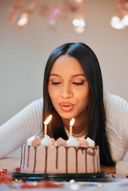 I hope all my wishes come true Shot of a young woman blowing candles on a cake while celebrating her birthday at home