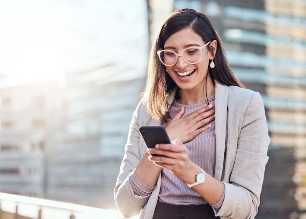 I just got the best review from a client Shot of an attractive young businesswoman standing alone outside and looking surprised while using her cellphone