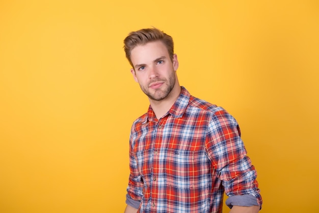 I like my style. male beauty standard. fashion model on yellow background. sexy unshaven man. denim clothing trend. barbershop salon. man in casual checkered shirt. handsome guy with bristle on face.