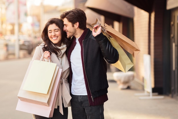 I'll buy it Happy couple with shopping bags man whispering to woman