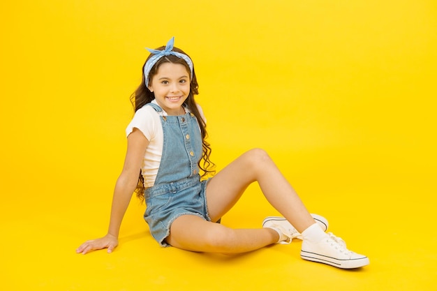 I love changing my style. Adorable small girl relax in fashion style. Little cute child with long brunette hair style on yellow background. Her style is a lot more casual.