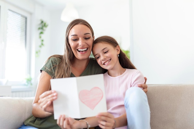 I love my you mom Attractive young woman with little cute girl are spending time together at home thanking for handmade card with love symbol and flowers Happy family concept Mother's day