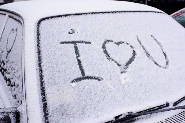 I love you Heart symbol on frozen window of the car Shape of heart drawn on snow on front window of the car Heart snow Christmas decorations and accessories