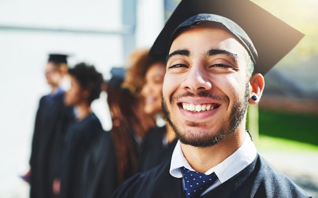 I made my family proud today Shot of a smiling university student on graduation day with classmates in the background