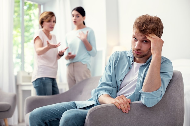 I need silence. Sad young man sitting in the armchair while wanting silence