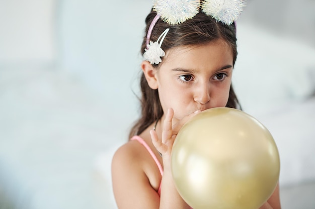 I want to see how big it gets Shot of an adorable little girl blowing up a balloon at her birthday party