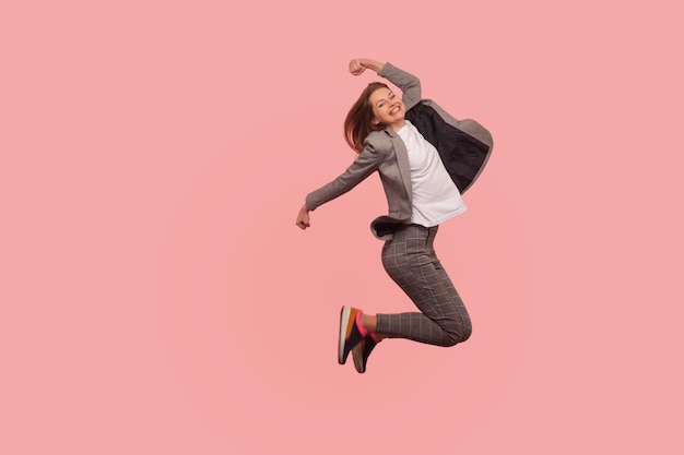 I39m champion Portrait of enthusiastic ecstatic happy businesswoman in elegant suit jumping carefree in air flying inspired by success celebrating goal achievement indoor studio shot isolated