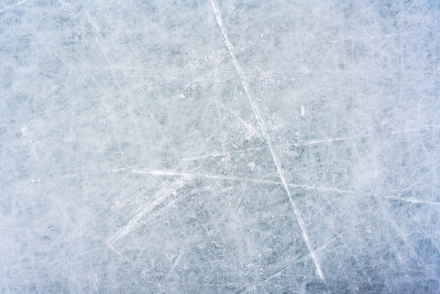 Ice background with marks from skating and hockey, blue texture of rink surface with scratches