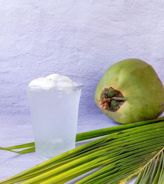 Ice coconut water drink in a plastic glass and coconut on white background