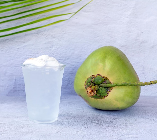 Ice coconut water drink in a plastic glass and coconut on white background