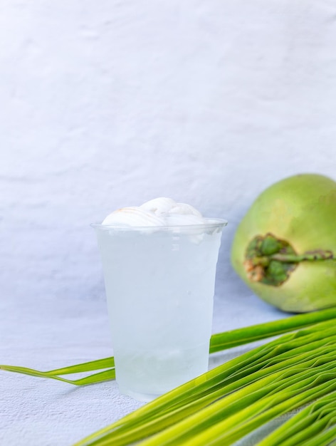 Ice coconut water drink in a plastic glass and coconut on white background