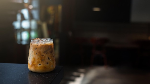 Ice coffee on a black table with cream being poured into it showing the texture