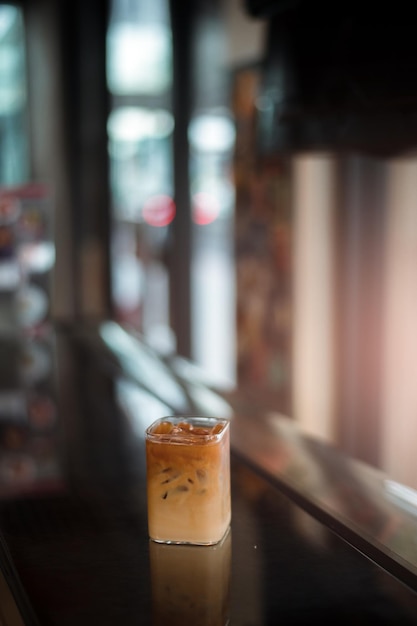 Ice coffee on a black table with cream being poured into it showing the texture