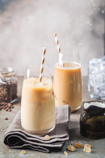 Ice coffee cold summer drink in a tall glass and coffee beans on a stone background.