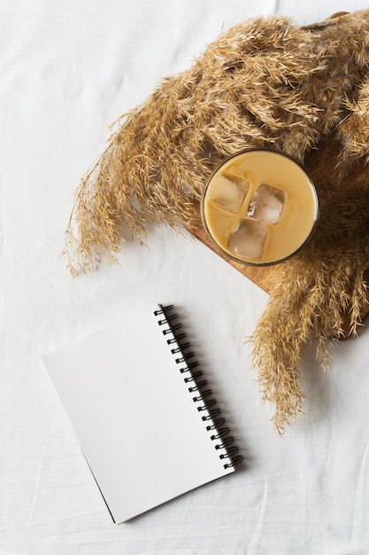 Ice coffee and dry flower or grass on white texture background