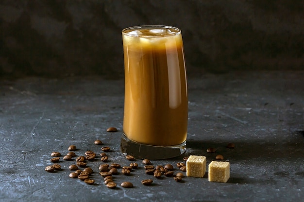 Ice coffee frappe in tall glass. Cool summer drink on a dark background in low key.