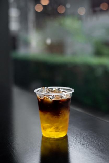 ice coffee in plastic glass on black table at cafe