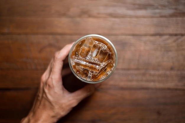 Ice coffee on a table with cream being poured into it showing the texture and refreshing