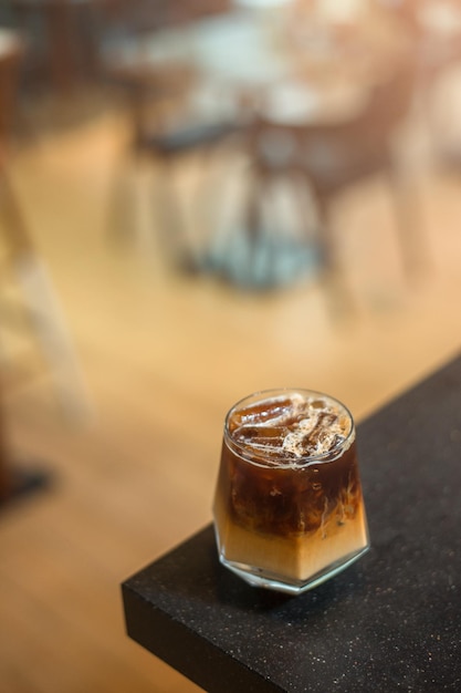 Ice coffee on a table with cream being poured into it showing the texture