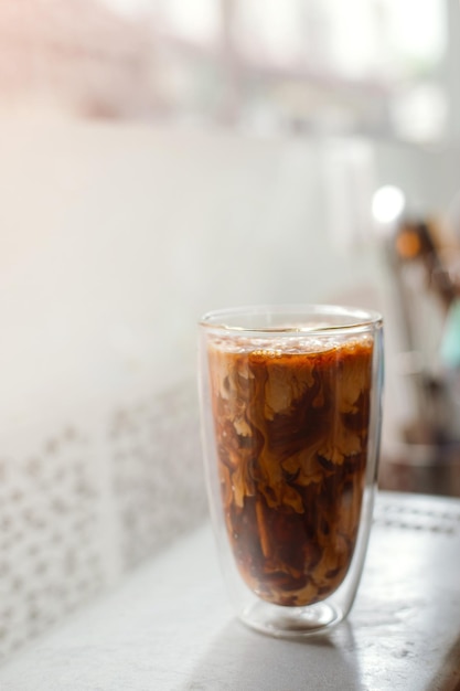 Ice coffee on a table with cream being poured into it showing the texture