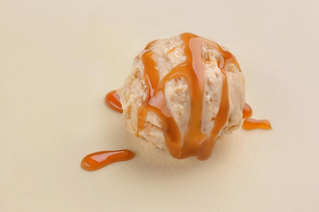 Ice cream ball with caramel sauce on light background