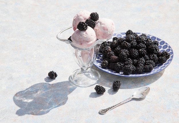 Ice cream balls in a glass bowl with blackberries on a light backgroundHorizontal orientation