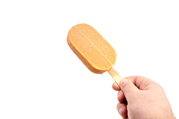 Ice cream in caramel glaze on a wooden stick in hand isolated on white