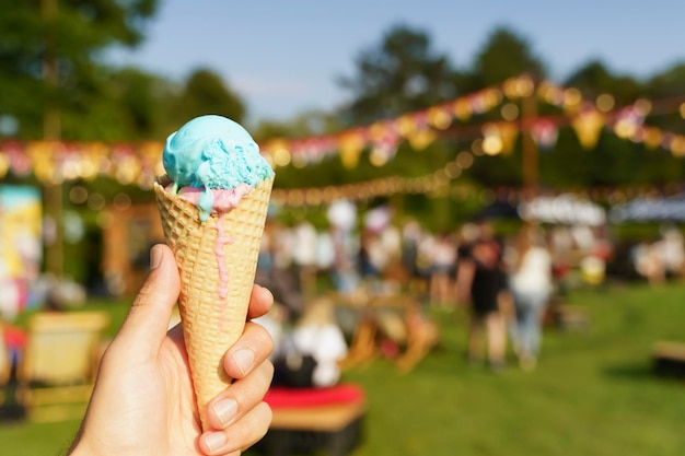 Ice cream cone in hand Sweet dessert on summer picnic blurred background Food summer ice cream