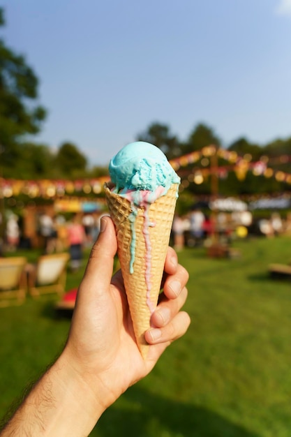 Ice cream cone in hand Sweet dessert on summer picnic blurred background Food summer ice cream