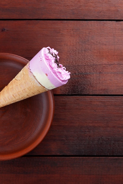 Ice cream cone with chocolate on clay plate Ice cream in waffle cup on wooden background Copy space