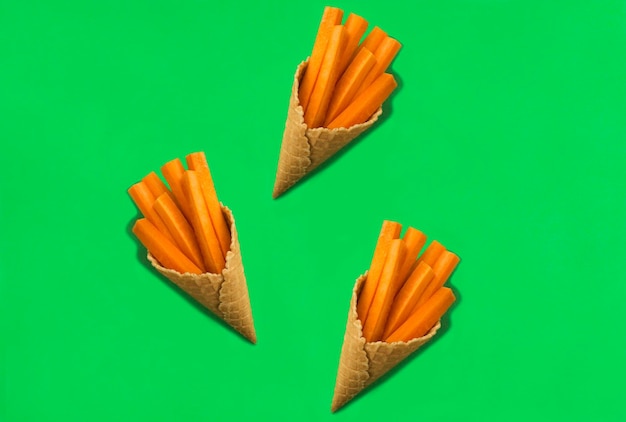 Ice cream cone with chopped carrot on the green background. Top view. Copy space.