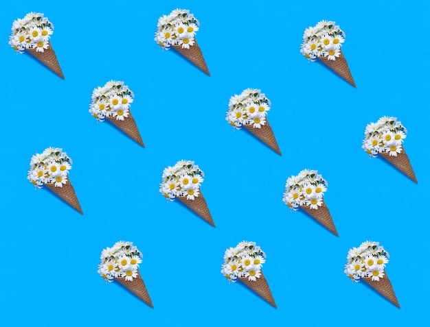 Ice cream cone with white chamomile on the blue background Pattern Flat lay Top view