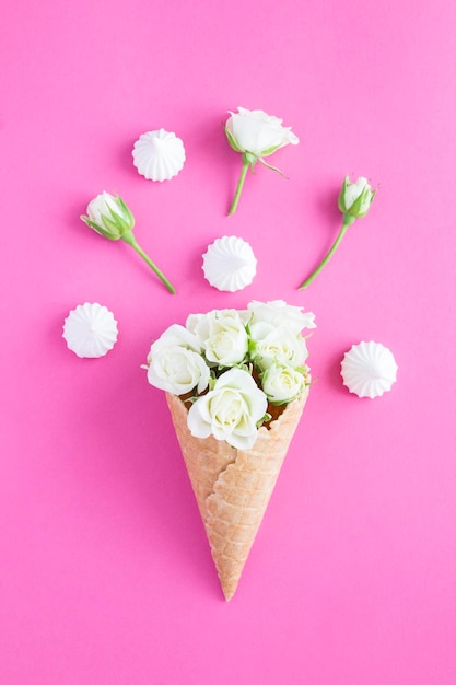 Ice cream cone with white roses and meringue the pink background Closeup Location vertical