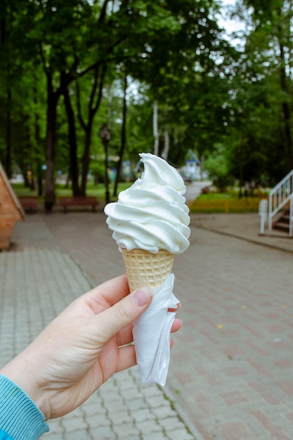 Ice cream horn in a paper napkin in a female hand