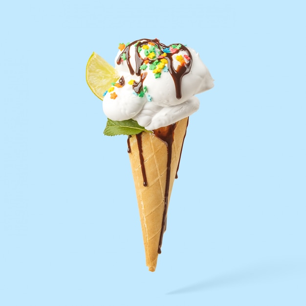 Ice cream in a horn with lime, mint and chocolate topping on a blue background.