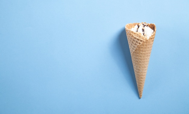 Ice cream in waffle cone on blue background.