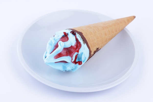 Ice cream in waffle cone on white plate closeup Frozen blue and red dessert Ice cream cone isolated on white background