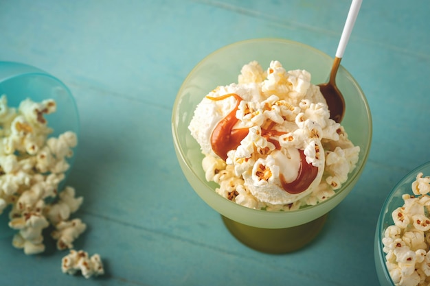 Ice cream with caramel and popcorn, blue background, copy space