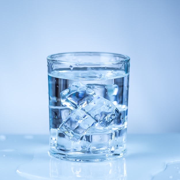 Ice cube in glass of water isolated on white surface