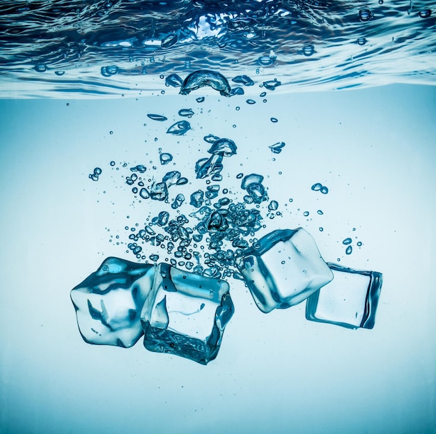 Ice cubes falling into the water sinking to the bottom. Abstract background.