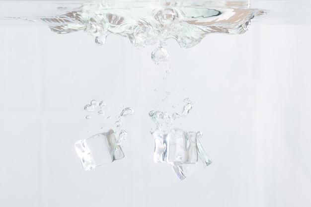 Ice cubes falling into water on white background