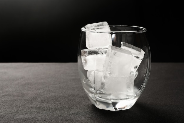 Ice cubes in glass on gray and black.