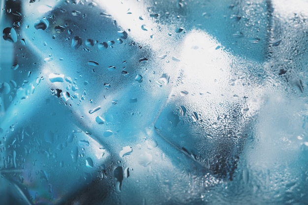 Ice cubes in a glass with crystal clear water on a blue background. Soft Selective Focus