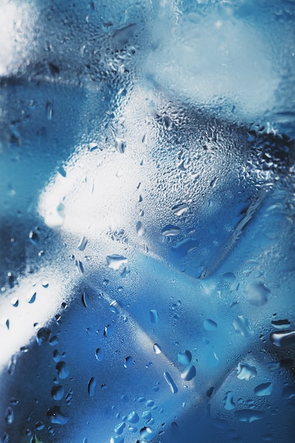 Ice cubes in a glass with refreshing ice water on a blue background