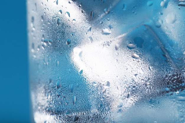 Ice cubes in a misted glass with drops of ice water closeup macro