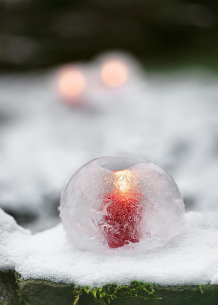 Photo ice globe lantern with red candle burning inside in the evening garden winter craft and ice art